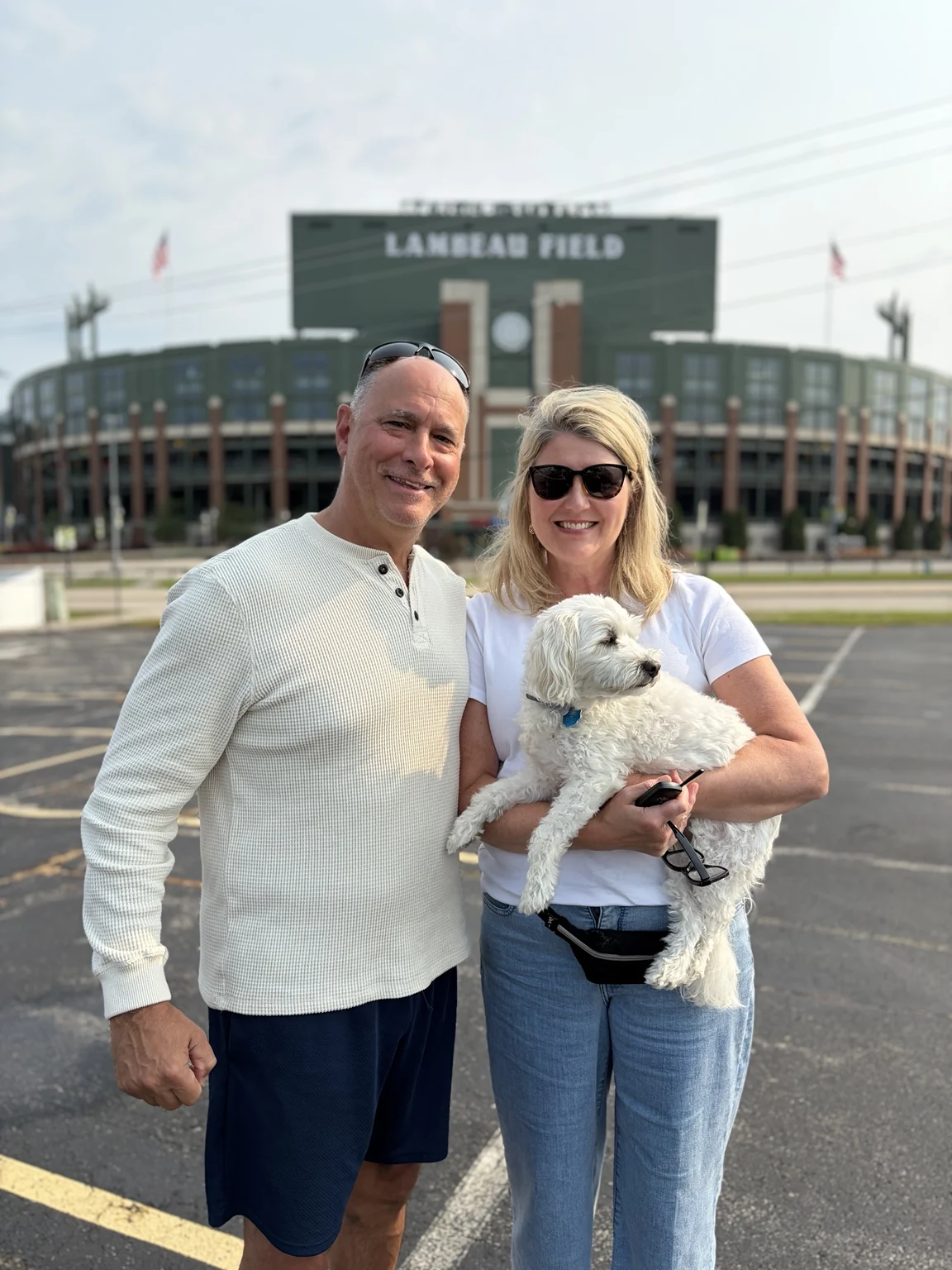 Guests standing across from Lambeau Field with their dog